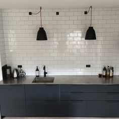 a kitchen with black cabinets and white subway tiles on the backsplash is shown