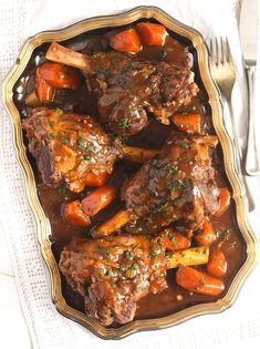 meat and carrots in gravy on a gold platter with a fork