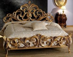 an ornate gold bed frame with pillows and blankets on top of it in a bedroom