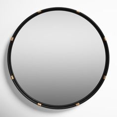 a round mirror hanging on the wall next to a black and gold trim around it