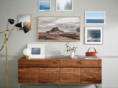 a living room with pictures on the wall and a wooden dresser in front of it