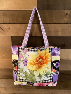 a multicolored floral tote bag hanging on a wooden wall