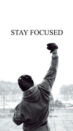 a black and white photo of a man raising his arms in the air with text that reads stay focused