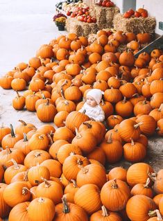 a pile of pumpkins sitting on the ground next to hay bales