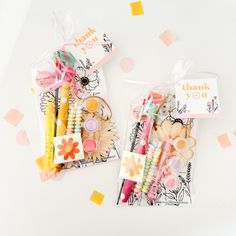 two bags filled with assorted items on top of a white table next to confetti