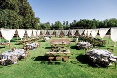 tables and chairs are set up in the middle of an open field with white tarps