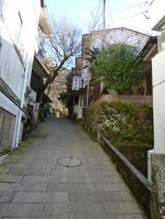 an alley way with buildings and trees on both sides, surrounded by cobblestones