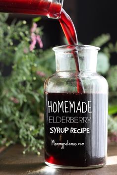 a glass bottle filled with liquid pouring out of it's top and the words homemade elderberry syrup being poured into it