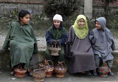 three women sitting on the ground with baskets in front of them and one woman wearing a headscarf