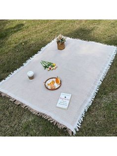 a picnic blanket on the grass with an egg and other food items sitting on it