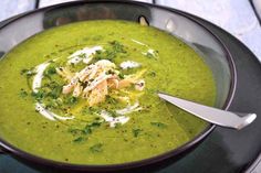 a bowl filled with green soup on top of a table