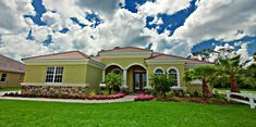 this is a beautiful house with nice landscaping on the front lawn and palm trees around it