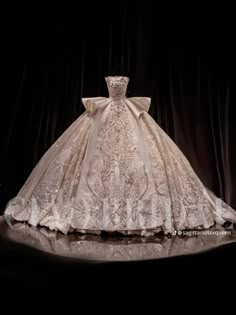 a white wedding dress on display in front of a black background