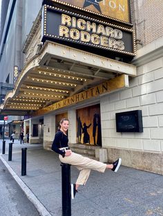 a woman sitting on top of a pole in front of a theater