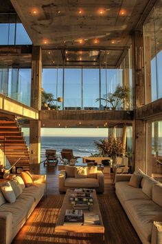 a living room filled with lots of furniture next to an ocean side house on top of a hill