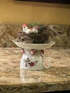 a bird's nest sitting on top of a white bowl filled with baby birds