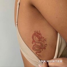 a woman with a dragon tattoo on her back and shoulder, showing it's red ink