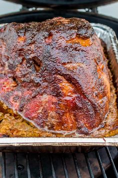 a meatloaf sitting on top of a metal pan next to an open grill