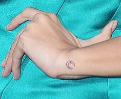 a woman's arm with a small crescent tattoo on the left side of her arm