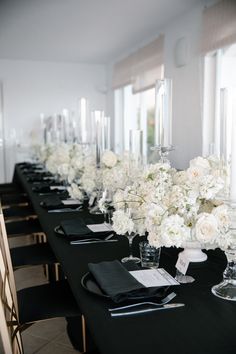 a long table with black linens and white flowers in vases on each side