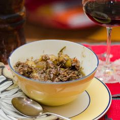 a bowl filled with food sitting on top of a plate next to a glass of wine