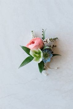 a pink rose and blue flowers on a white background with greenery in the center