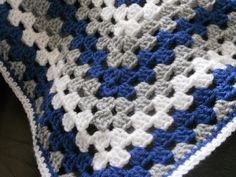 a blue and white crocheted blanket on top of a couch