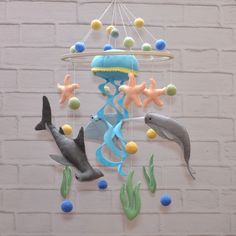 a mobile with sea animals and fish hanging from it's sides on a brick wall