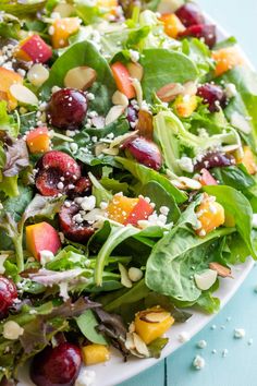 a salad with cherries, almonds and feta cheese on a white plate