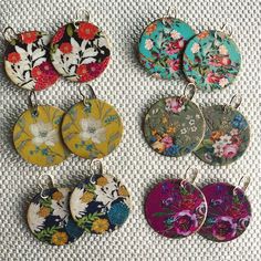 six different flowered round pendants on a white tablecloth with flowers in them