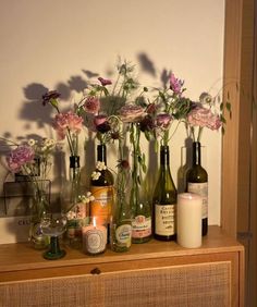 flowers and candles are arranged in vases on a dresser