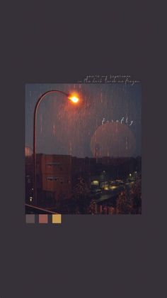 an image of rain falling on a street light and buildings in the background at night