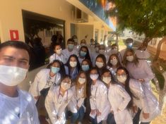 a group of doctors in white coats and face masks posing for a photo with each other