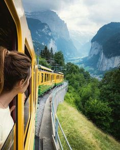 a woman looks out the window of a train as it travels through mountains and valleys