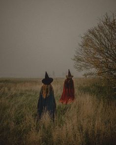 two women in witches costumes walking through tall grass