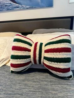 a crocheted bow tie sitting on top of a bed next to a pillow