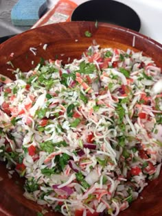 a wooden bowl filled with coleslaw on top of a stove