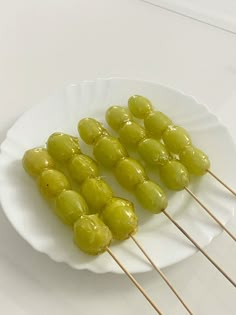 several skewers of green olives on a white plate