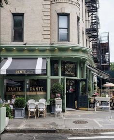 an outdoor cafe with tables and chairs on the sidewalk in front of a tall building