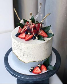 a white cake with berries and leaves on top