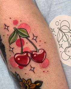 a tattoo with two cherries on the side of her leg, and stars around it