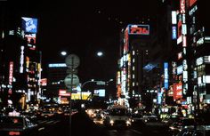 a city street filled with lots of tall buildings and traffic at night in the dark