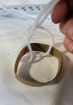 a person is holding a piece of tape and thread on top of a white cloth