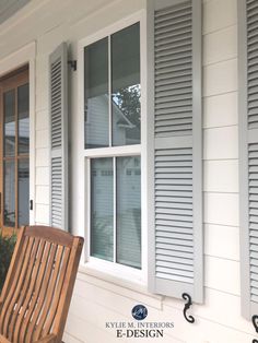 a wooden bench sitting in front of a window on the side of a white house