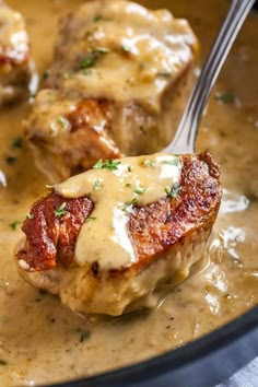 two pieces of meat covered in gravy with a fork sticking out of it