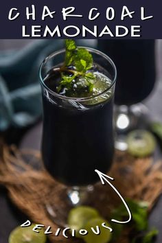 a glass filled with black liquid and garnished with limes on the side