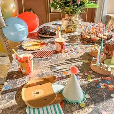 a table with many different items on it and balloons in the air behind it,