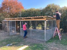 two people standing on top of a chicken coop