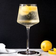 a glass filled with liquid next to lemons