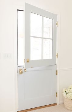 a white door with a basket of flowers on the floor